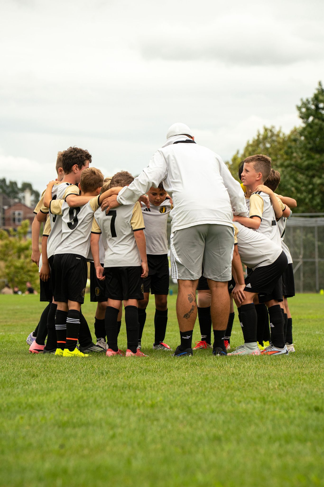 Coach leading team huddle in white jacket